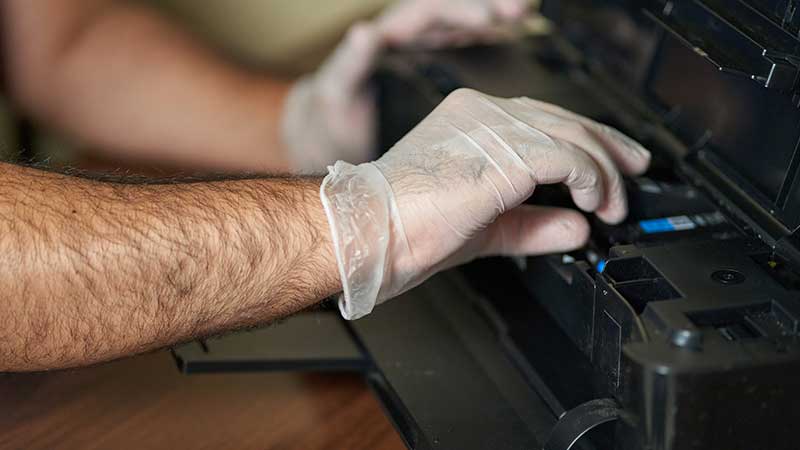 Homem com luvas a limpar impressora